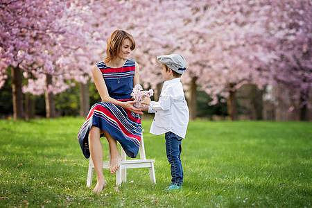 39086059-beautiful-kid-and-mom-in-cherry-blossom-spring-park-child-giving-flowers-to-mother-mothers-day-celeb
